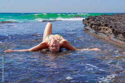 Woman reclining on surf covered rock shelf eros nature photo