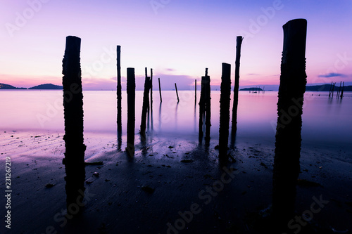 Long exposure image of Dramatic sky seascape with Old wooden pole in the sea sunset or sunrise scenery background. © panya99