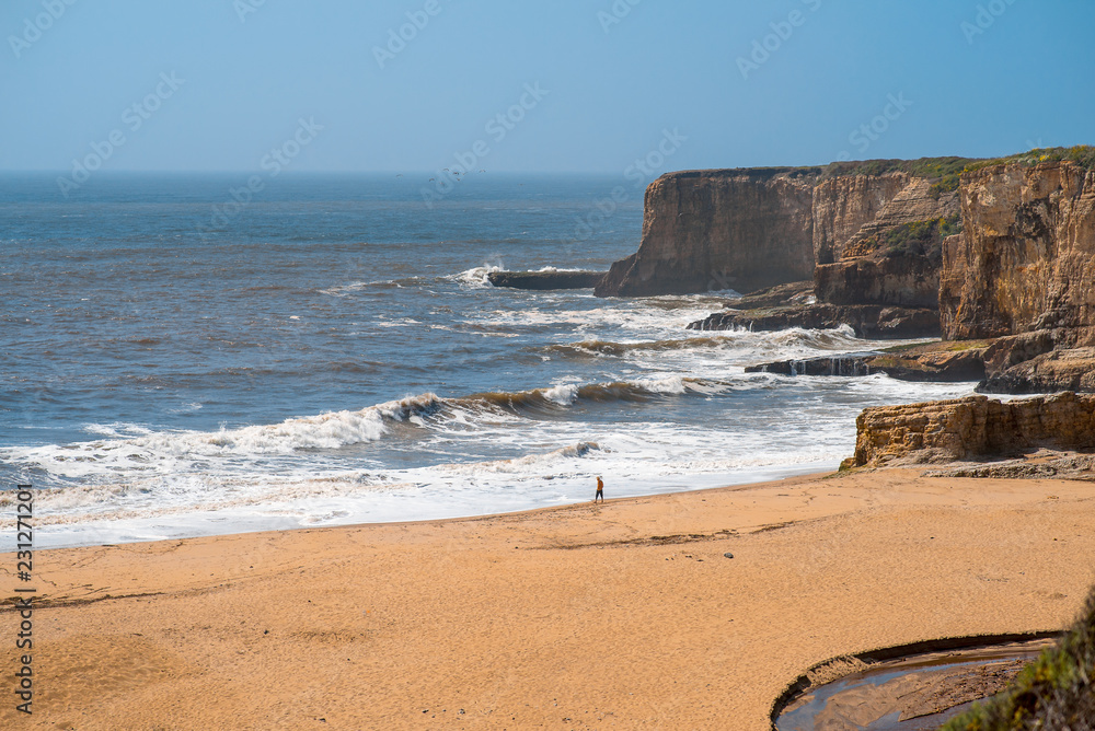 Rocky sea shore with storm waves. Man is walking along beach