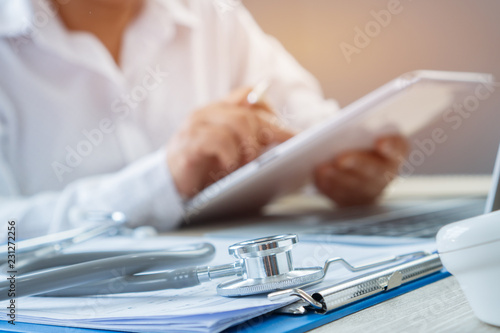 Healthcare medical concept, Hands Doctor's writing and working by stylus for order medication on tablet prescription online record patient at office hospital or clinic. Focus stethoscope on keyboard photo