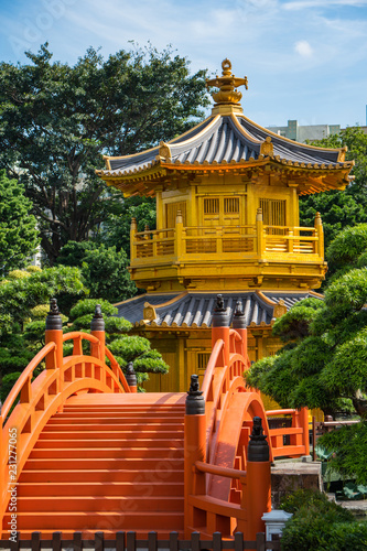 Gold pagoda amongst Buddhist pines with a red bridge. Peace and calm
