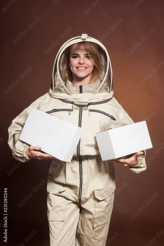 Fototapeta premium The girl the Beekeeper in a protective suit holds boxes in hand
