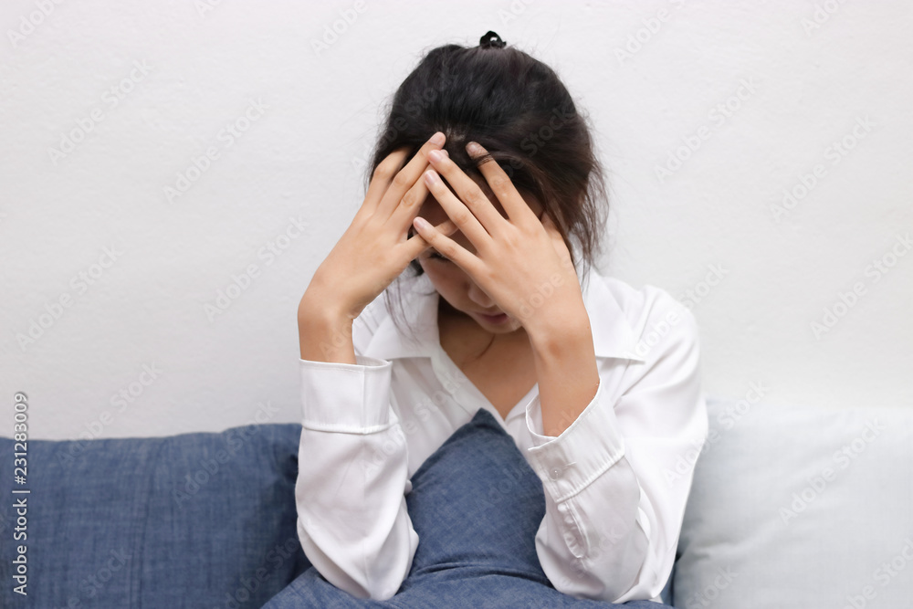 Ttired stressed young Asian woman covering face with hands in living room. Ttired stressed young Asian woman covering face with hands in living room.