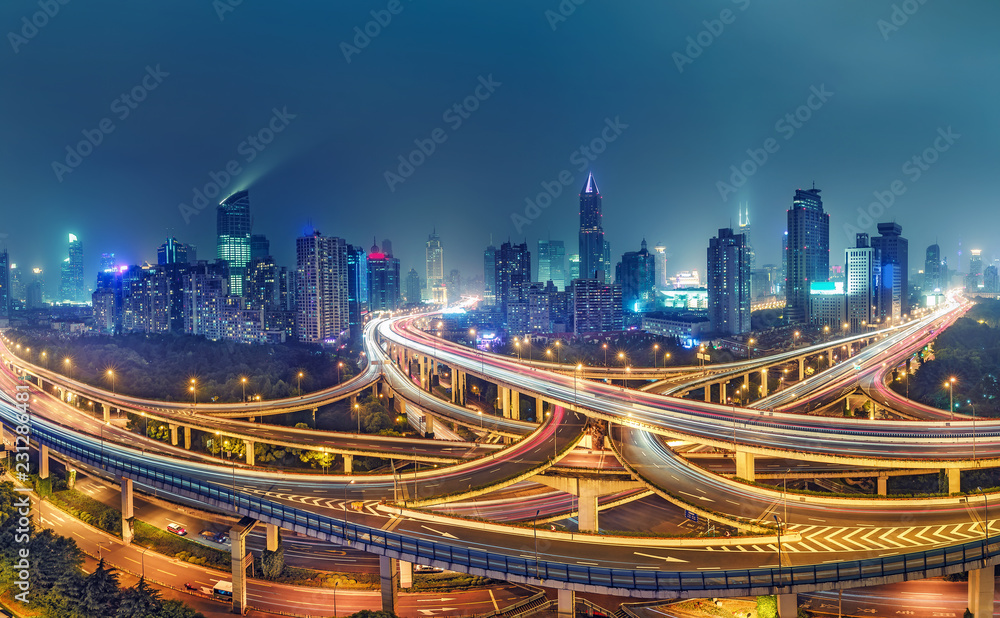 Fototapeta premium Widok na słynne skrzyżowanie autostrad w Szanghaju w Chinach, z oświetlonymi autostradami i drapaczami chmur.