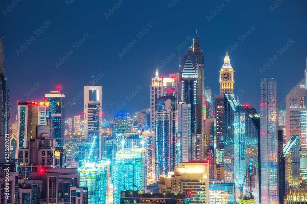 Obraz premium Spektakularna miejska panorama z kolorowymi iluminacjami miasta. Widok z lotu ptaka na drapacze chmur w Dubaju, Zjednoczone Emiraty Arabskie.