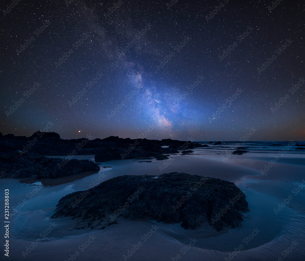 Vibrant Milky Way composite image over landscape of Freshwater West beach on Pembrokeshire Coast in Wales