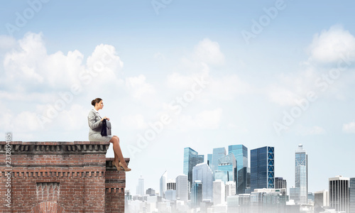 Businesswoman or accountant on brick roof against modern city scape