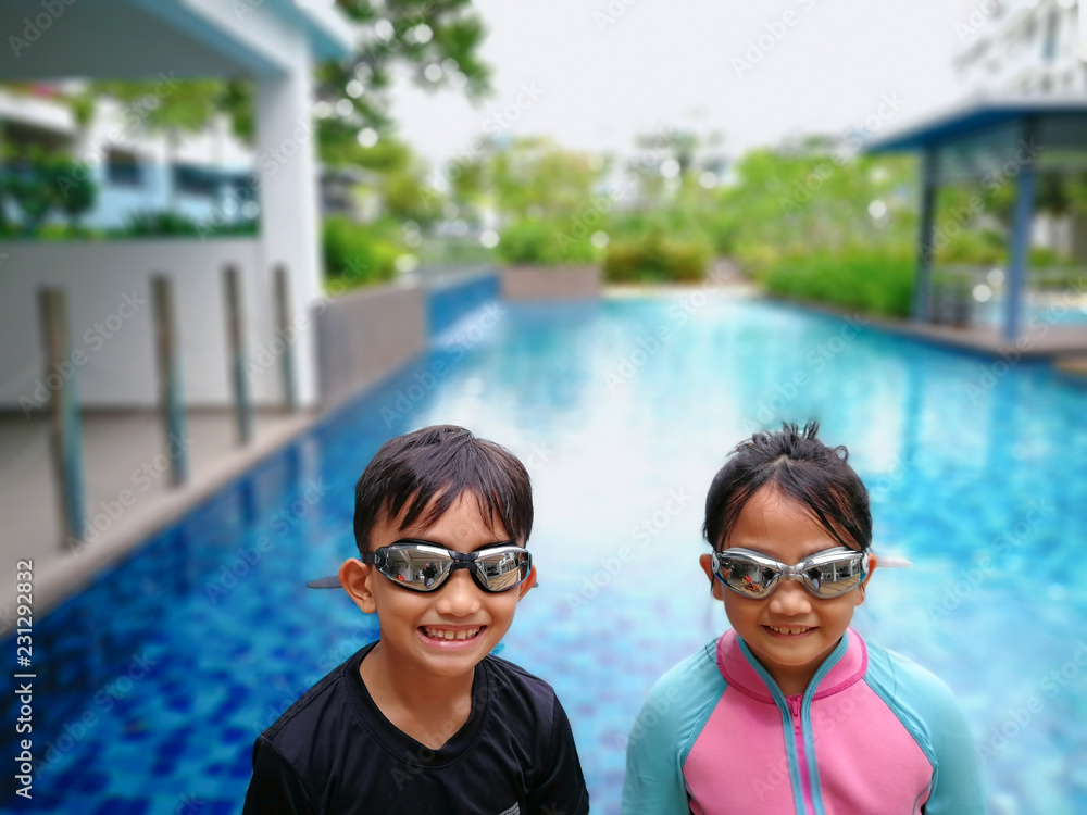 Asian kids standing happily before entering the swimming pool.