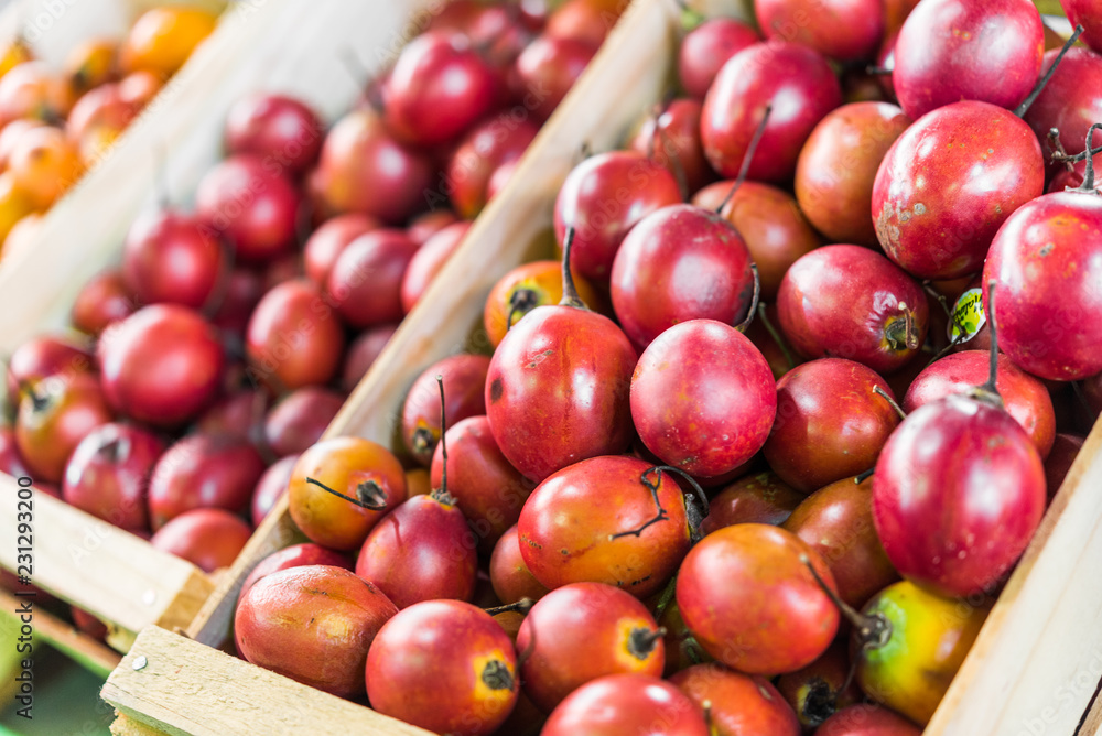 Organic tamarillo tree tomato exotic fruit on display in wooden boxes at a street food market fair festival Organic tamarillo tree tomato exotic fruit on display in wooden boxes at a street food market fair festival
