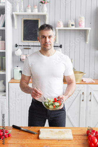 Portrait of handsome smiling man chopping vegetables in the kitchen. The concept of eco-friendly products for cooking.