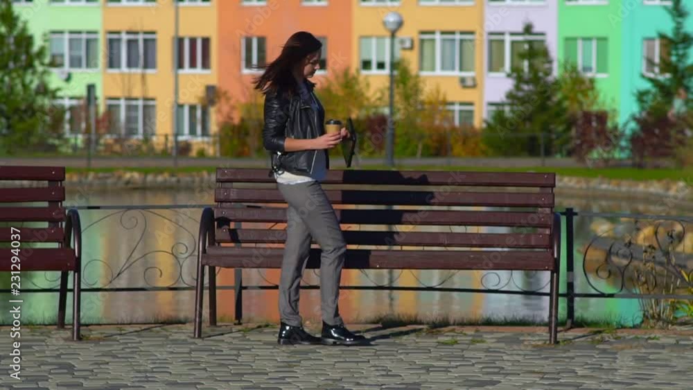 The girl sits on a bench in the Park to work on the tablet. The girl sits on a bench in the Park to work on the tablet.