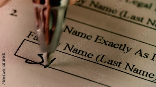 A pen writes in a family / last name on a census or US immigration document photo