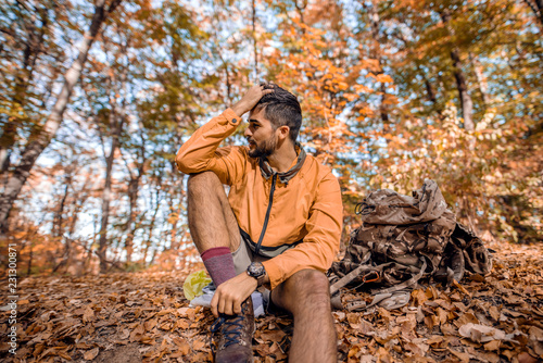 Hiker sitting on ground in woods in autumn. © dusanpetkovic1
