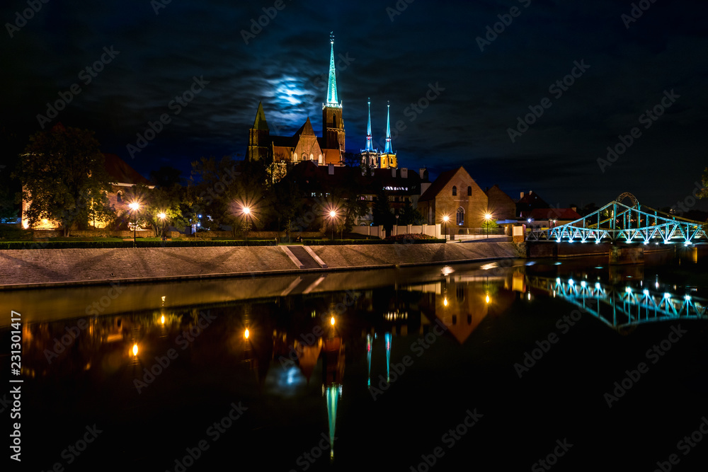 Reflection scenic with moon view of the Old Town architecture and Oder river embankment  and historical district Ostrow Tumski with the spires illuminated of the gothic cathedral in Wroclaw, Poland