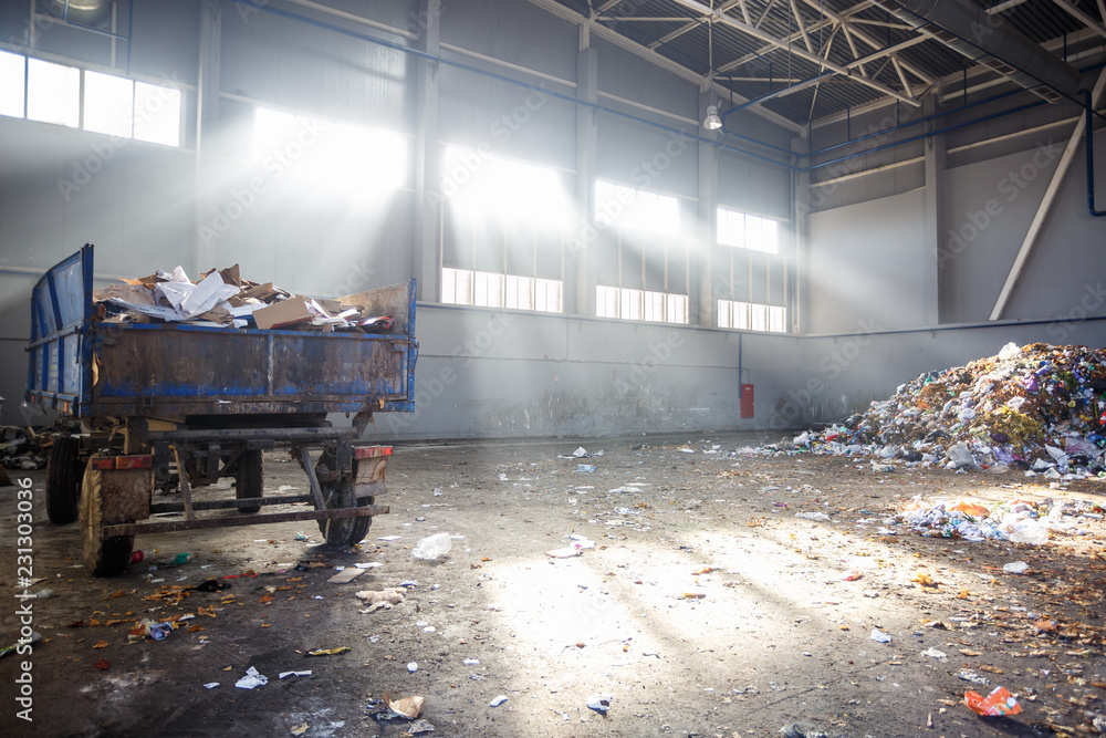 trash sorting and recycling workshop with trailer at the waste processing plant with sun rays. Separate garbage collection. Recycling and storage of waste for further disposal.