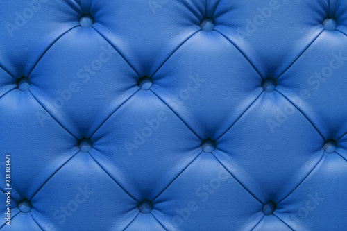 Background of leather blue sofa, stitched buttons.