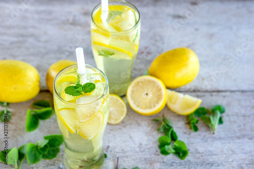 refreshing lemonade glass with lemon,  ice and green mint on wooden table 