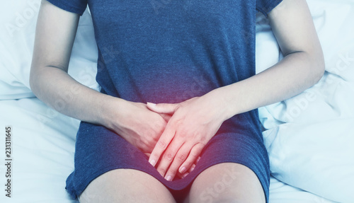 Beautiful Attractive Asian woman wearing white shirt sitting on bed have a bladder pain or uti pain after wake up in the morning feeling so illness,Healthcare Concept.color tone
