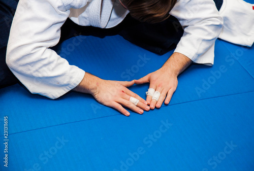 Aikidoka makes a bow during aikido training. Hands on blue tatami photo