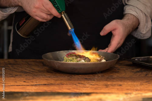 Chef preparing food with fire burner © Vera