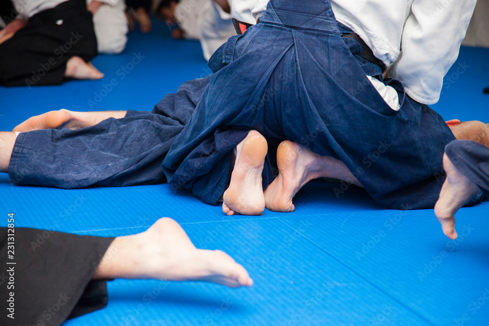 Φωτογραφία Aikidoki are fighting in the stalls on the background of blue tatami