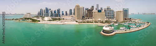 The skyline of Doha, Qatar. Modern rich middle eastern city of skyscrapers, aerial view in good weather, midday, during hot dry summer, with view of marina and beach of Persian Gulf/Arabian Gulf photo
