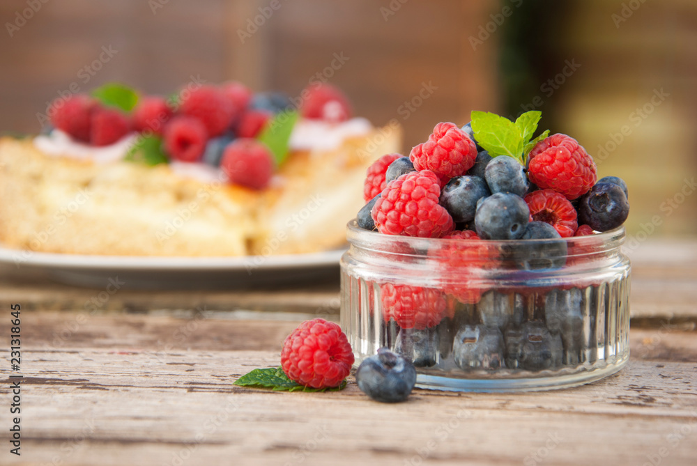 Small glass bowl full of blueberries and raspberries, ready to eat, placed on rustic wood desk. Small glass bowl full of blueberries and raspberries, ready to eat, placed on rustic wood desk.