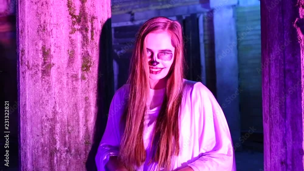 Woman with dead bride make-up for Halloween standing by the car in the white bride dress in the dark at abandoned house Woman with dead bride make-up for Halloween standing by the car in the white bride dress in the dark at abandoned house