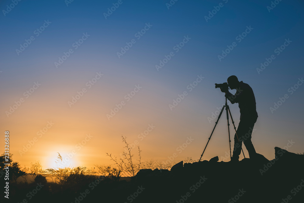 Silhouette of black photographer at sunset