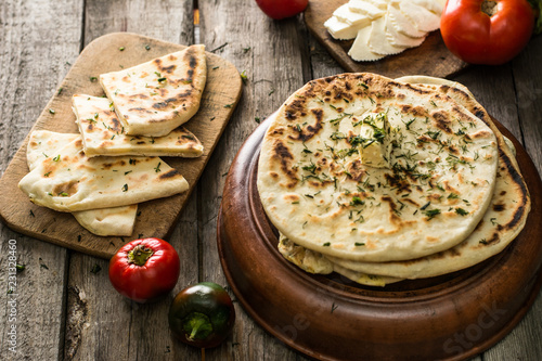 Pita bread on wooden board with feta cheese and tomatoes and pepper. Still life of food. Georgian cuisine. Spanish food. National cuisine. Traditional dish on wooden table. Mediterranean cuisine. photo