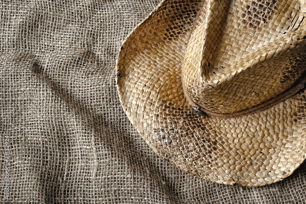 Fototapeta premium Western style straw hat on burlap. Top down view.