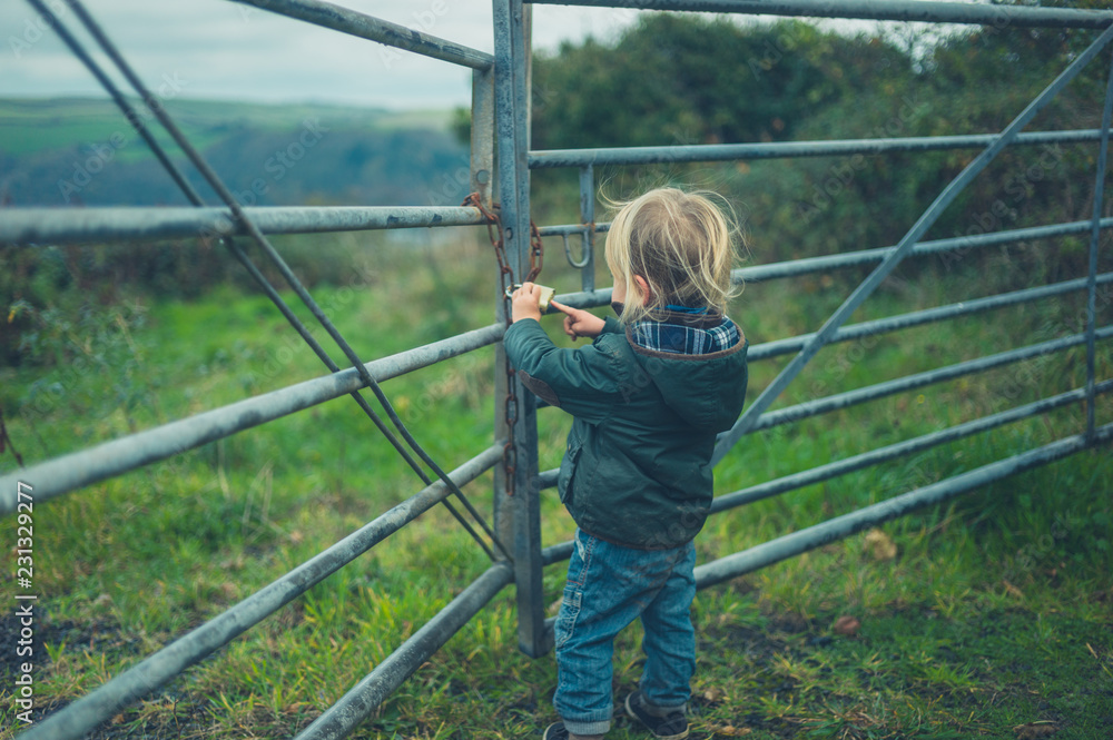 Little toddler standing by fence in the countryside Little toddler standing by fence in the countryside