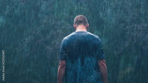 Rear view of man walking towards forest in rain