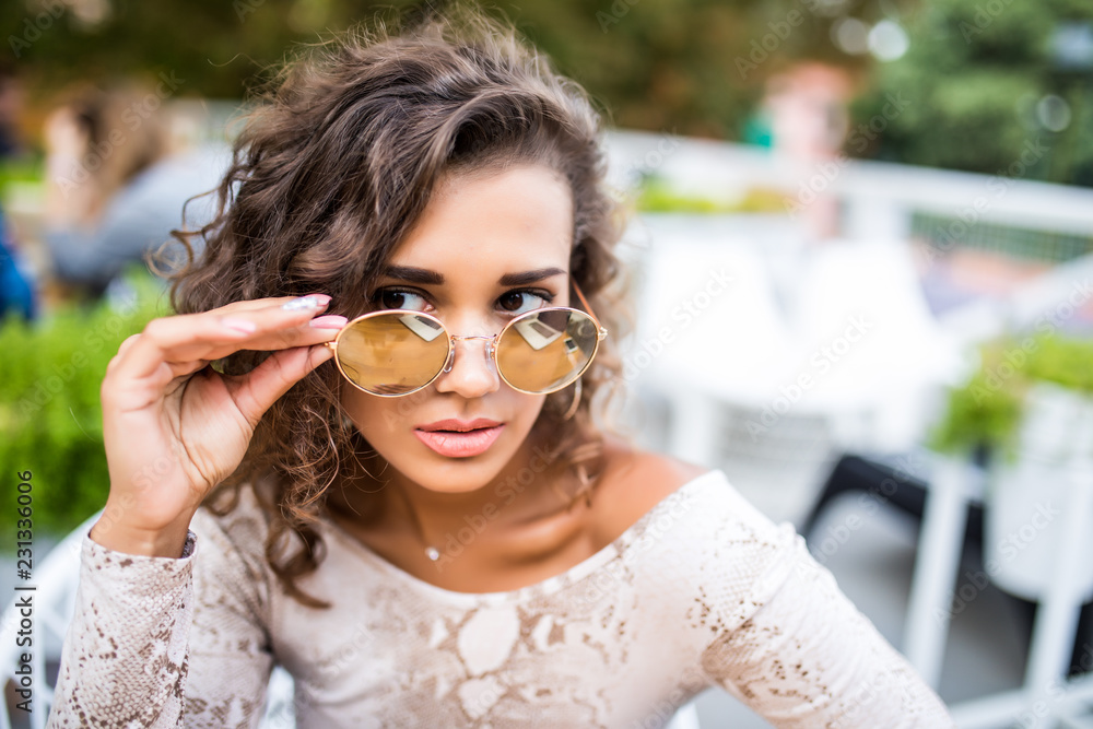 Young beautiful latin woman in sunglasses relaxing in the restaurant.