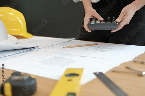 architect working on house blueprint of real estate project at workplace. engineer using calculator. building construction concept