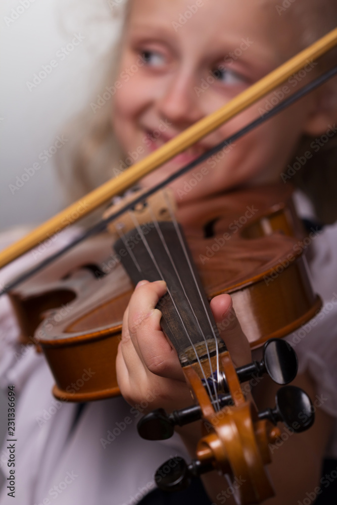 Cute little girl in bright blouse plays the violin close-up on a gray background Cute little girl in bright blouse plays the violin close-up on a gray background