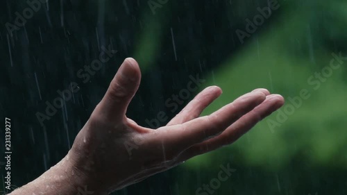 Slow motion 180fps: Man holds his open  hand / palm out in the  pouring rain