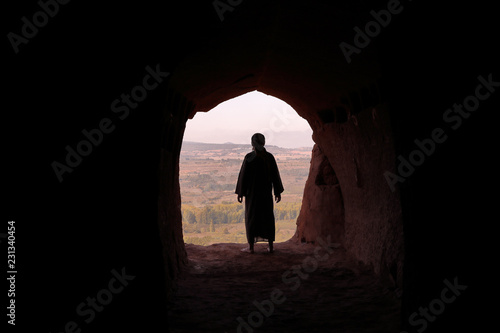Fototapet MAN WITH TUNIC AND PALESTINIAN SCARF IN A CAVE LOOKING A VALLEY
