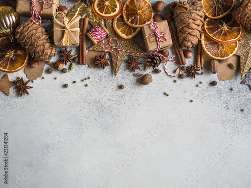 Brown, gold and orange Christmas or New Year background with Christmas decorations, spices, nuts, dried orange slices, pine cones. Copy space. Top view
