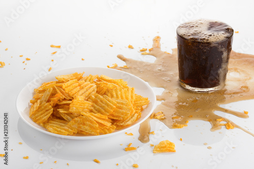 Fotografía chips with cola on a bright table, spilled soda, junk food - concept