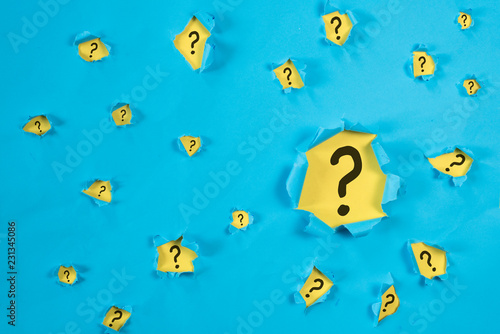 Torn blue paper revealing QUESTION MARK on yellow paper. concept of questions, faq, q&a, problem, riddle and quiz background photo