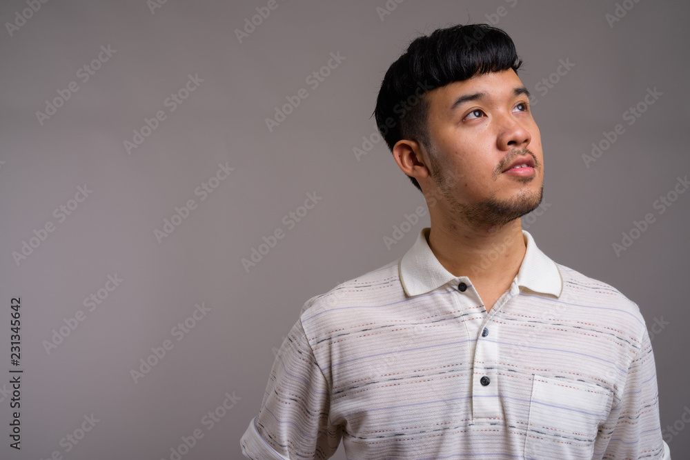 Portrait of young Asian man against gray background Portrait of young Asian man against gray background