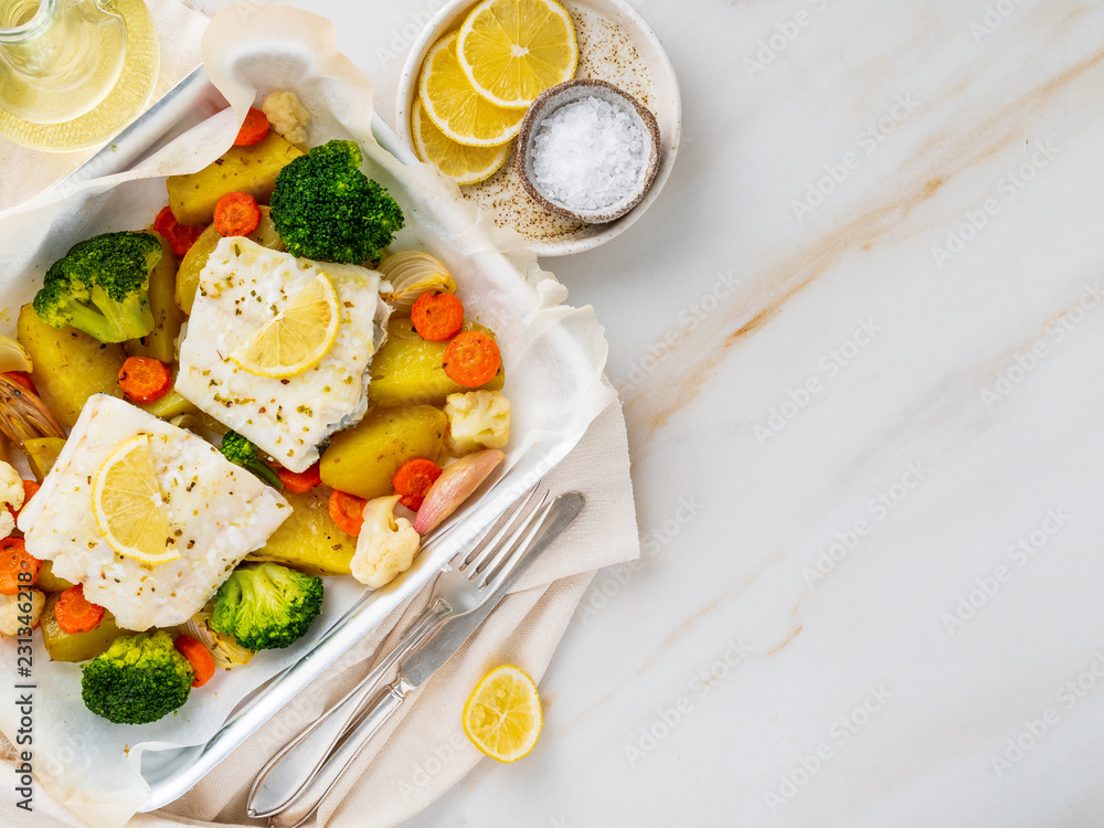 Fish cod baked in the oven with vegetables - healthy diet healthy food. Light white marble table, copy space, top view Fish cod baked in the oven with vegetables - healthy diet healthy food. Light white marble table, copy space, top view