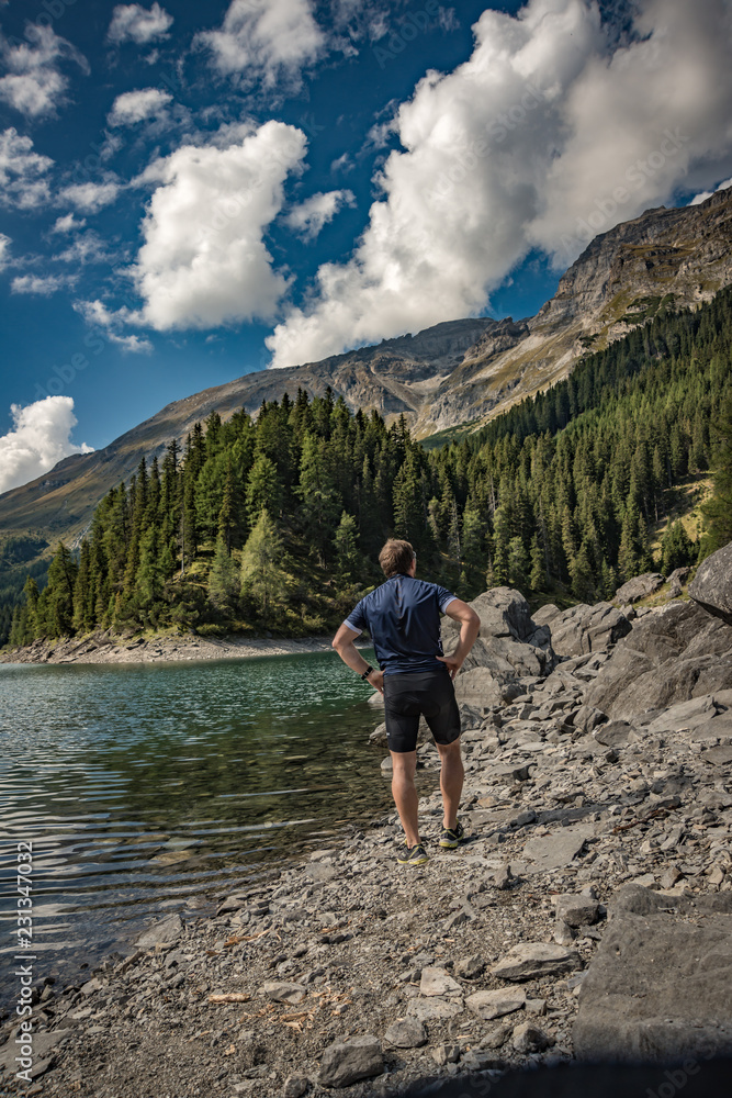 On the mountainlake On the mountainlake Alpine pastures with a deep blue lake, green meadows and a blue sky with fleecy clouds, in summer, with biker