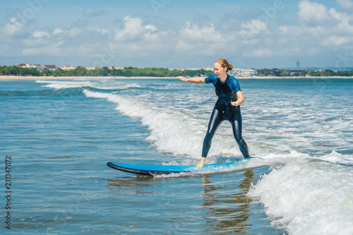 Joyful young woman beginner surfer with blue surf has fun on small sea waves. Active family lifestyle, people outdoor water sport lesson and swimming activity on surf camp summer vacation
