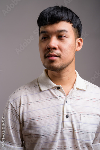 Portrait of young Asian man against gray background
