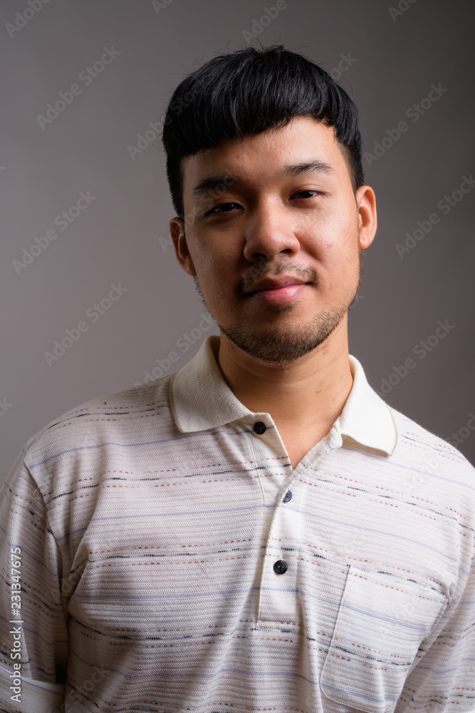 Fototapeta premium Portrait of young Asian man against gray background