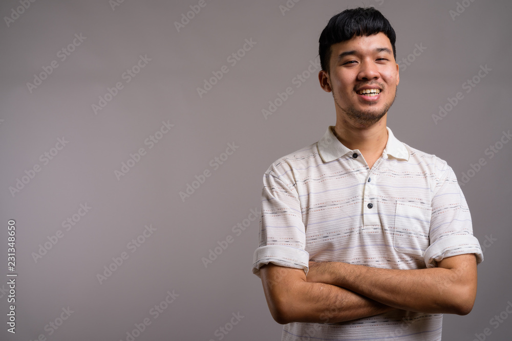 Portrait of young Asian man against gray background Portrait of young Asian man against gray background