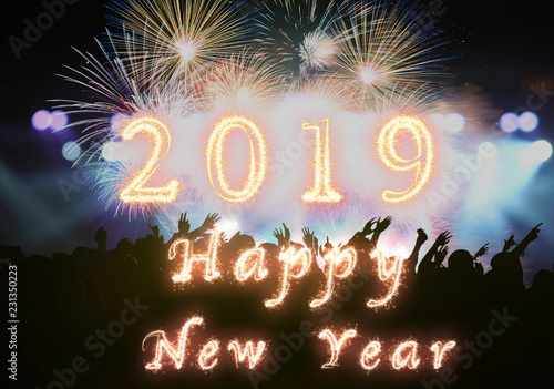 Happy new year 2019 written with Sparkle firework on Concert crowd in silhouettes of Music fanclub with show hand action for celebrate with fireworks, Xmas celebration concept