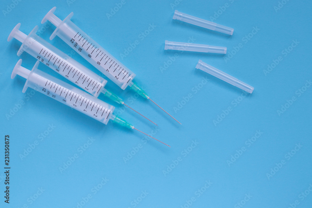 Obraz premium Medical plastic syringes with a needles on blue background. Therapy concept. Selective focus